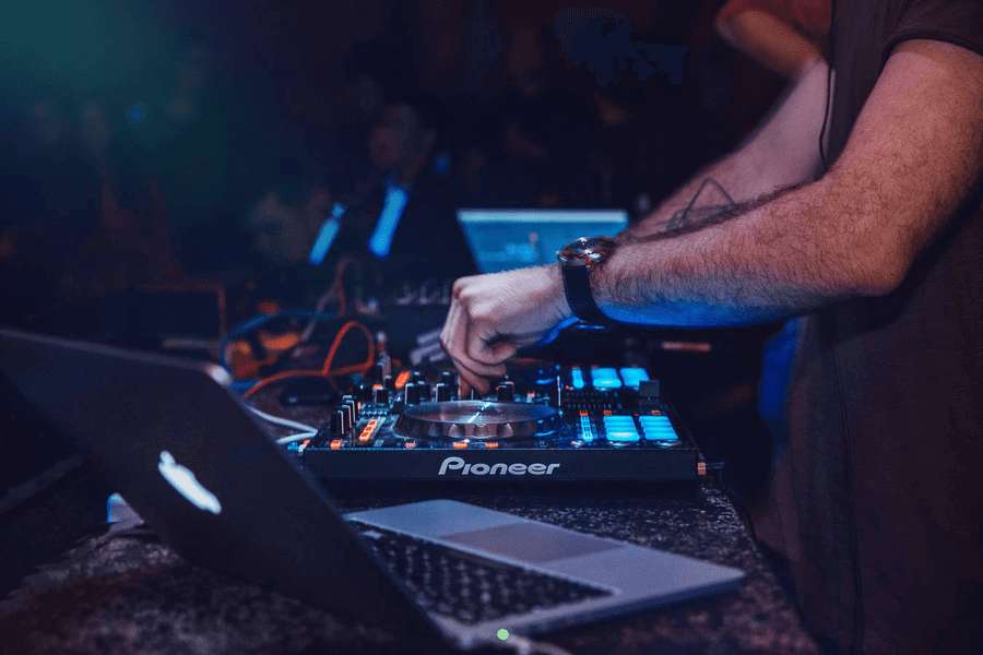 Un DJ se tient devant ses platines et tables de mixage lors d'un concert.