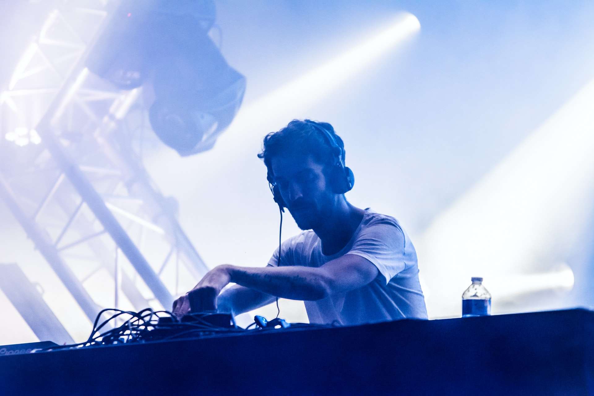 Un DJ a répondu à une annonce pour un concert live, il joue un DJ set en live sur une scène éclairée par des projecteurs.