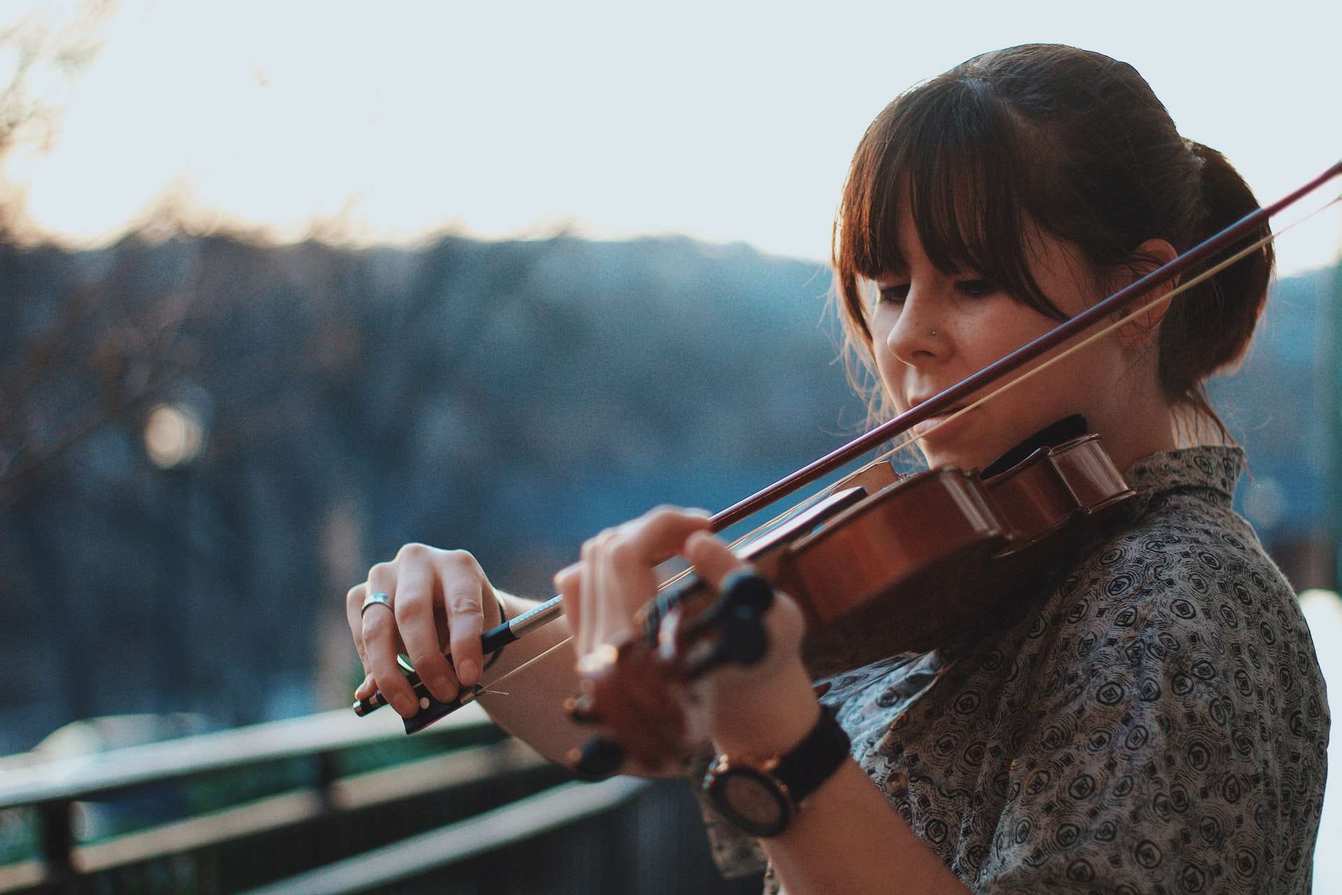 Une violoniste a répondu à une annonce musicien pour jouer de son instrument dehors, sur un balcon face à la nature.