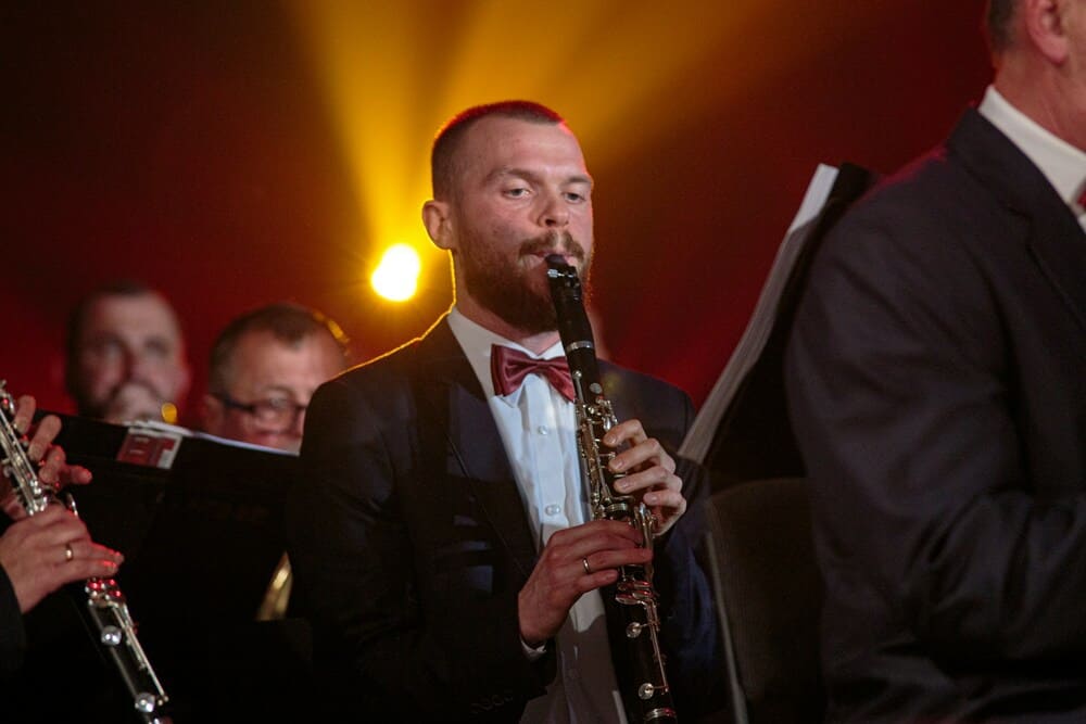 Un homme joue du hautbois parmi un orchestre.