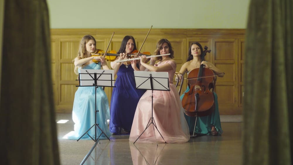 Un groupe de quatre femmes jouent de divers instruments dont la flûte.