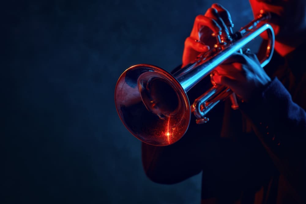 Un homme joue de la trompette dans une lumière rouge et bleue.