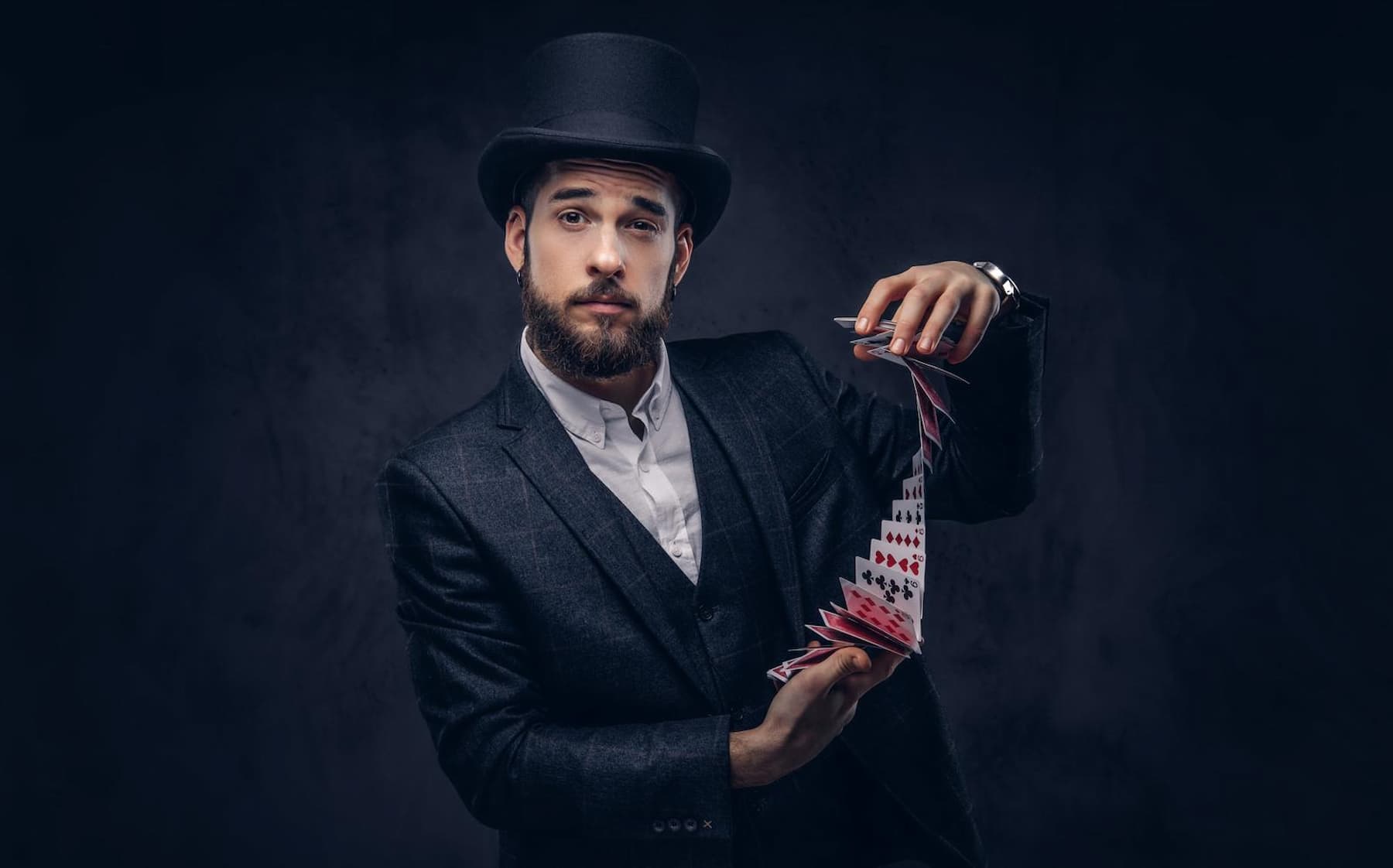 Magicien en costume et haut-de-forme faisant cascader un jeu de cartes