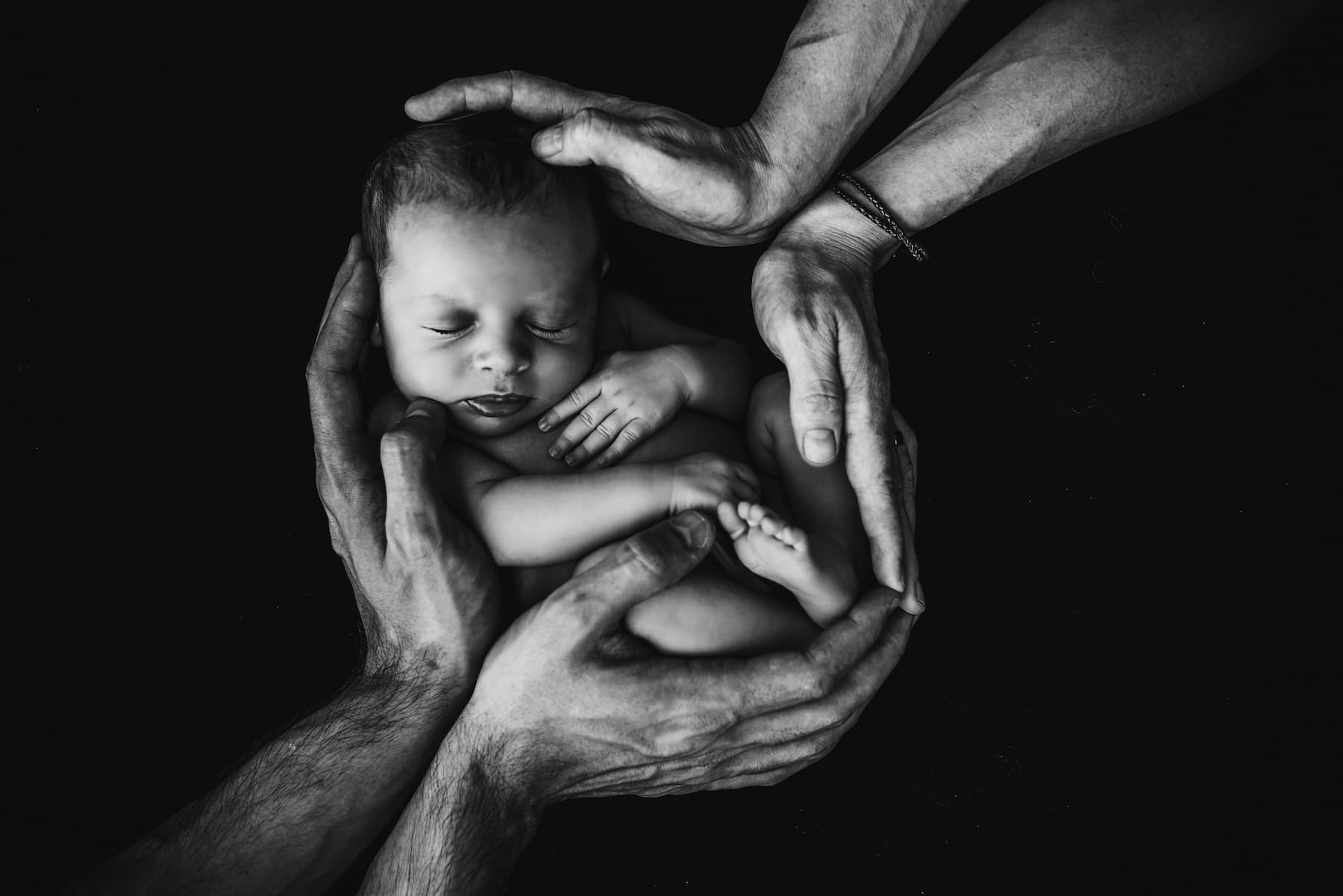 Mains des parents entourant leur bébé