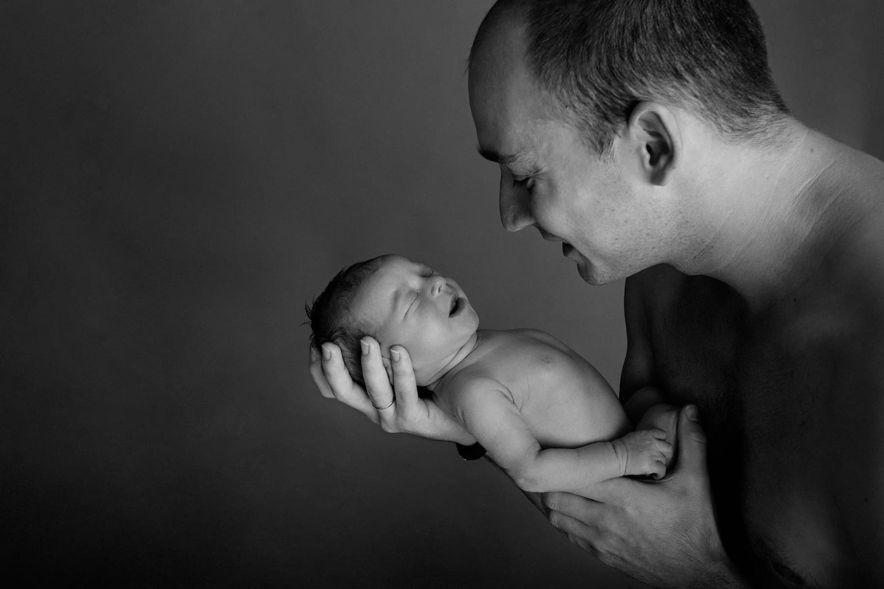 Photo nourrisson dans les bras de son papa en noir et blanc
