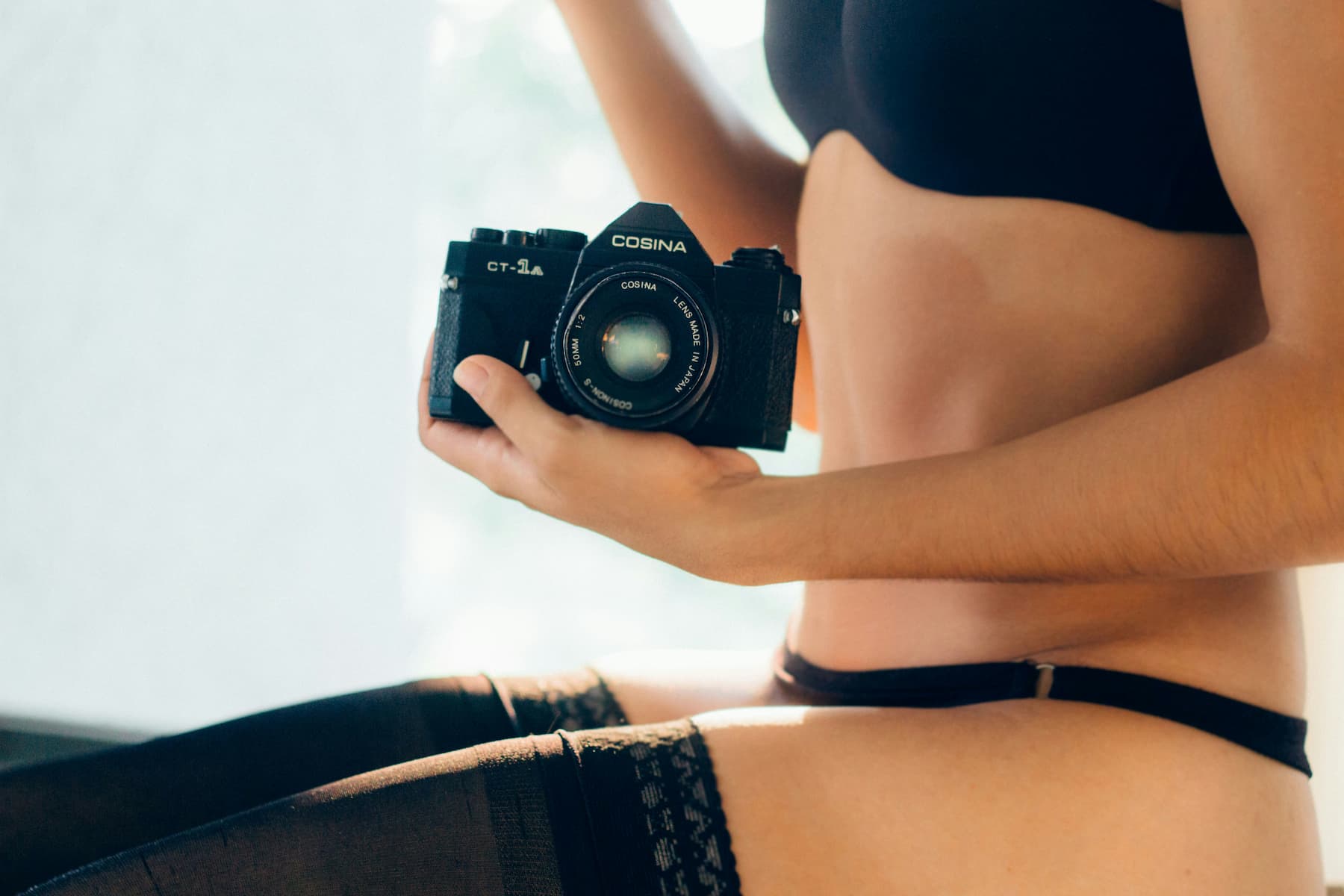 Femme en sous-vêtements tenant dans ses mains un appareil photo
