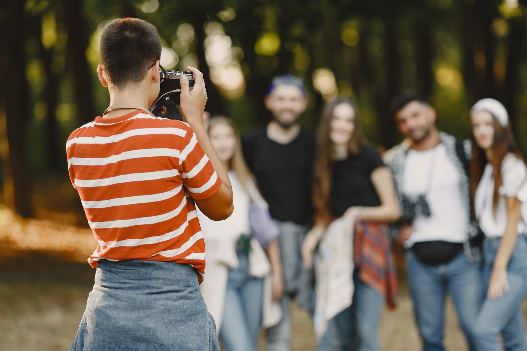 Photographe prend une photo d'un groupe d'amis dans une forêt